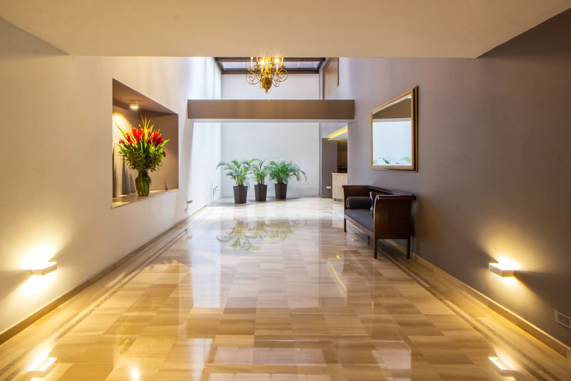 Hall com piso polido espelhado refletindo o lustre